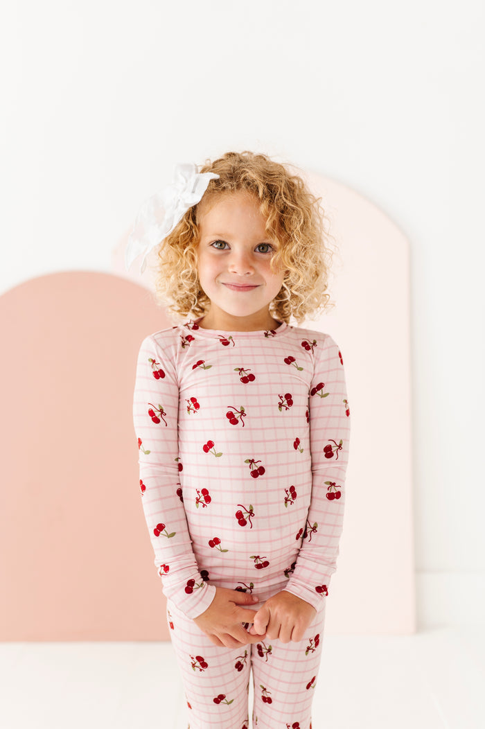 Child wearing a pajama set with cherry pattern on a white background