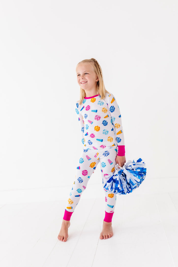 Child wearing colorful pajamas with paw prints and a pom-pom on a white background