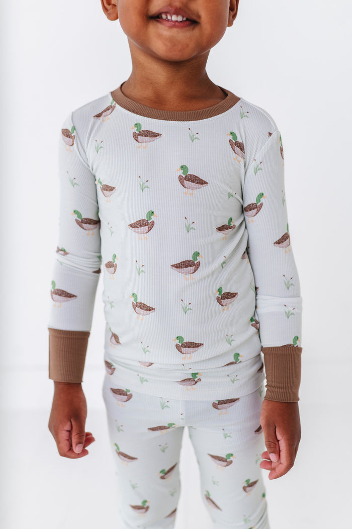 Child wearing a pajama set with duck pattern on a white background